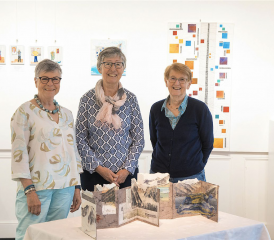 Trois des cinq membres d’Art-tex (de gauche à droite, Patricia Fuentes, Marianne Bender et Martine Mercier) posent devant le livre montagne de la Valaisanne au centre. RÉGINE GAPANY