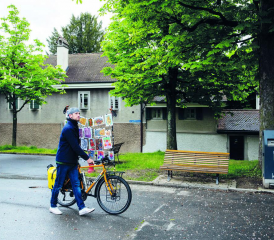 A la galerie Trait Noir, Lucien Pilloud affiche ses œuvres et son iconique vélo avec ses cartes postales installées dessus. CÉLINE GRANGER