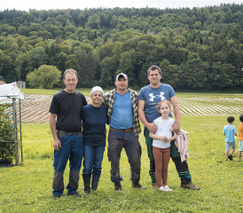 Daniel et Agnès Perroud prennent soin de leurs petits fruits et légumes avec l’aide de Lucian Matara (au centre). La famille de Ludovic Criscione (ici avec sa fille) reprendra les rênes du domaine en 2025. RÉGINE GAPANY