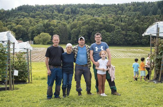 Daniel et Agnès Perroud prennent soin de leurs petits fruits et légumes avec l’aide de Lucian Matara (au centre). La famille de Ludovic Criscione (ici avec sa fille) reprendra les rênes du domaine en 2025. RÉGINE GAPANY